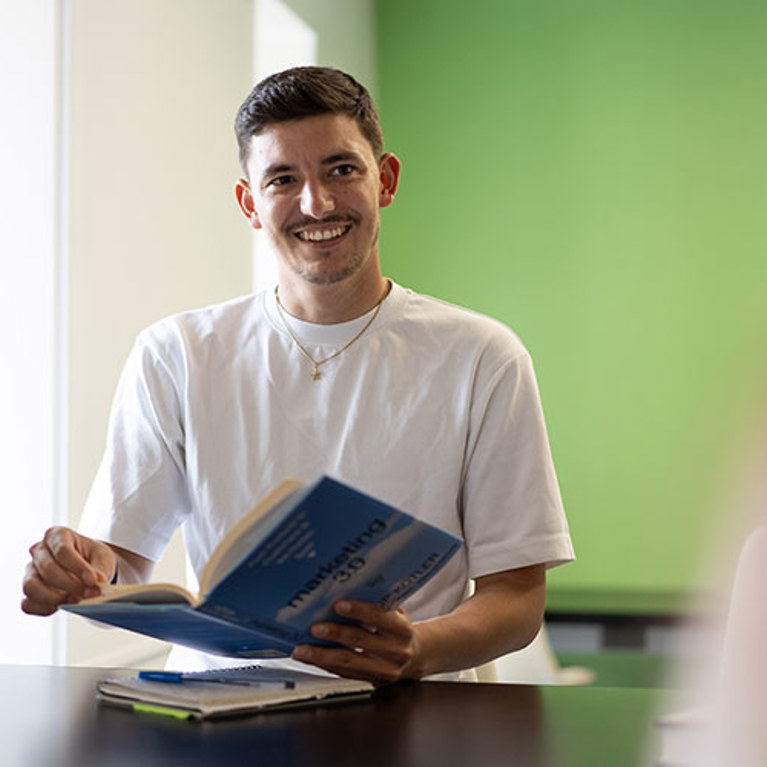 A man smiling and reading a marketing book